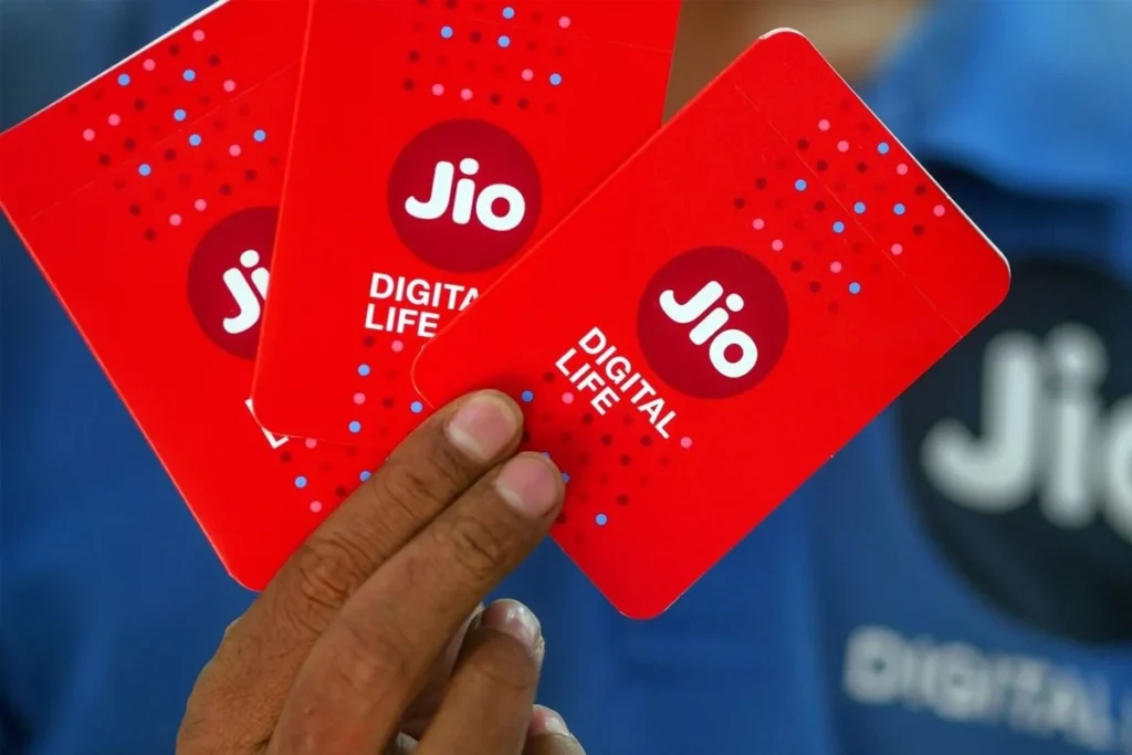 Indian couple sitting on a sofa using laptop and phone showing 5G Wi-Fi symbol, representing India’s digital shift during the jio tariff hike 2025.